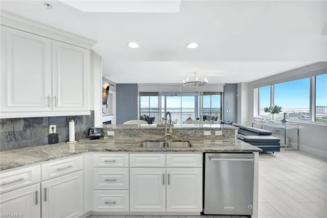 a kitchen with kitchen island granite countertop a sink and white cabinets