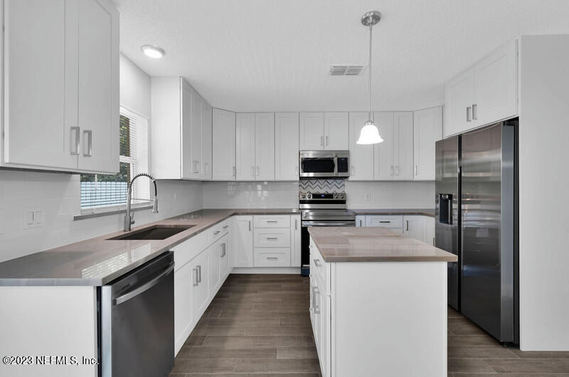 692 Largo Lane Macclenny, FL 32063 - Photo 12 of 41 a kitchen with stainless steel appliances granite countertop a sink a stove a refrigerator cabinets and a kitchen island