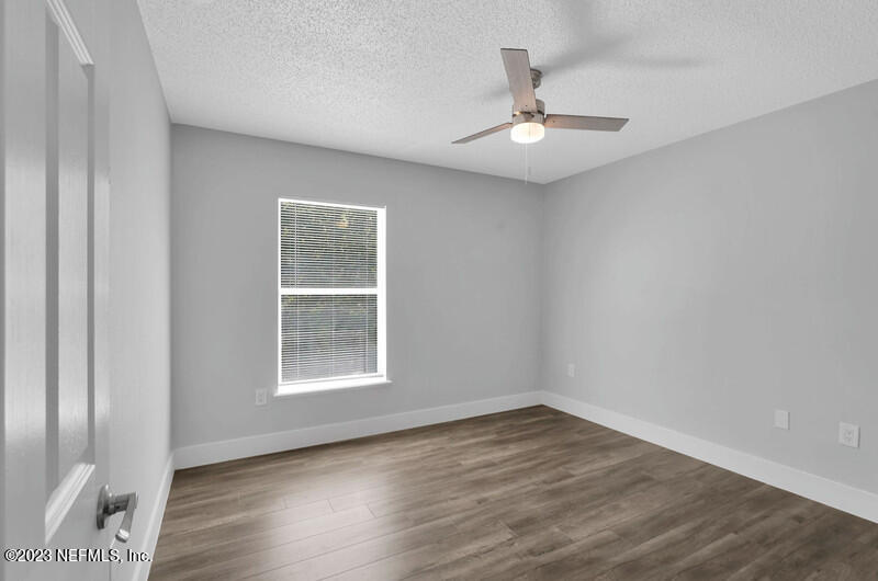 692 Largo Lane Macclenny, FL 32063 - Photo 17 of 41 an empty room with wooden floor chandelier fan and windows