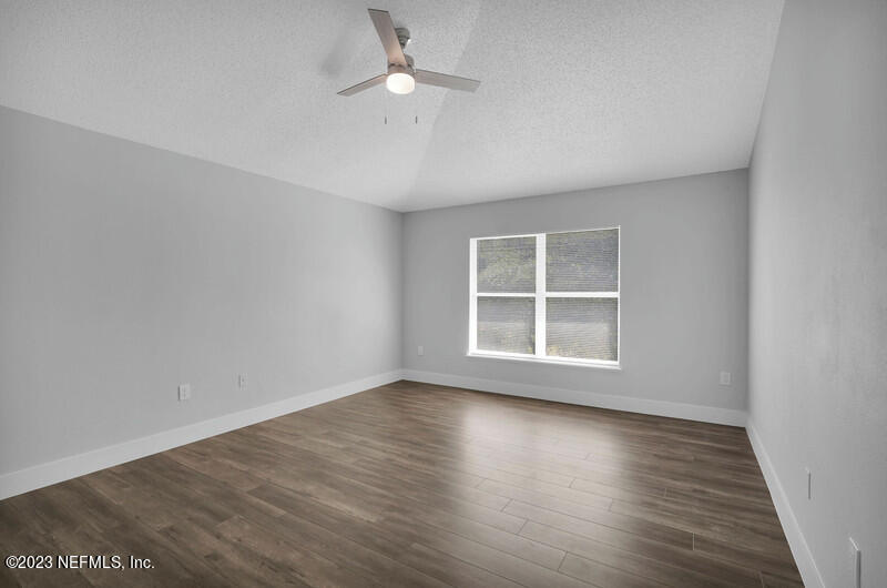692 Largo Lane Macclenny, FL 32063 - Photo 28 of 41 an empty room with wooden floor chandelier fan and windows