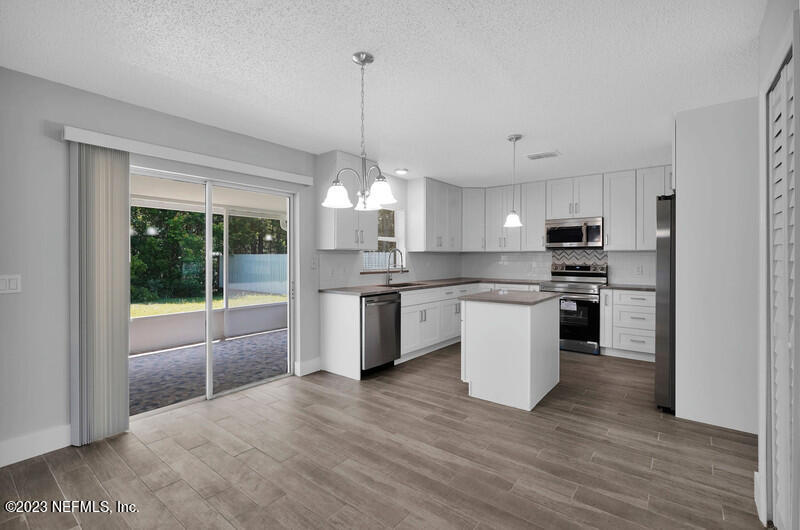 692 Largo Lane Macclenny, FL 32063 - Photo 35 of 41 a large kitchen with stainless steel appliances kitchen island granite countertop a stove a sink dishwasher a refrigerator and white cabinets with wooden floor