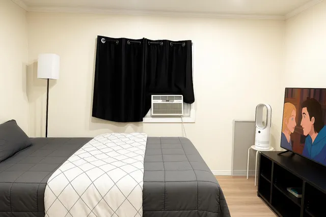a bedroom with a bed and a flat tv screen on dresser
