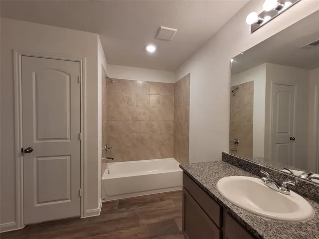 a bathroom with a granite countertop sink a mirror and a bathtub