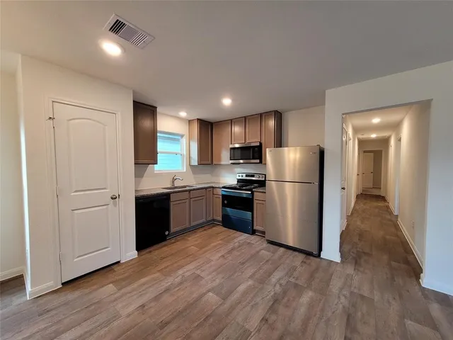 a kitchen with a refrigerator a sink and a stove top oven