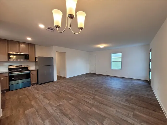 a kitchen with granite countertop a stove a oven a sink cabinets and wooden floor