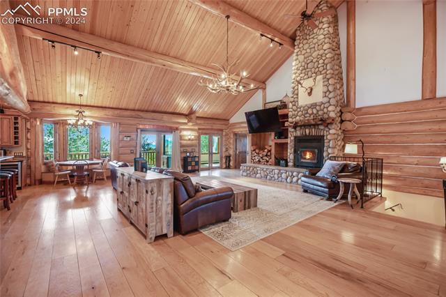 616 Summit Road Hartsel, CO 80449 - Photo 14 of 50 Living room featuring a fireplace, wood-type flooring, wooden ceiling, beam ceiling, and log walls