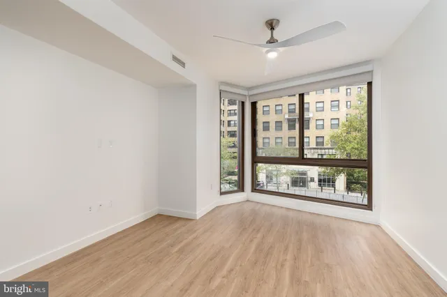 an empty room with wooden floor and windows