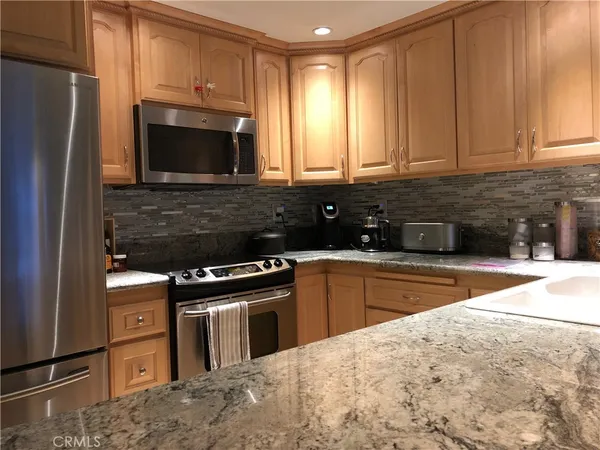 a kitchen with stainless steel appliances granite countertop a stove a sink and a microwave