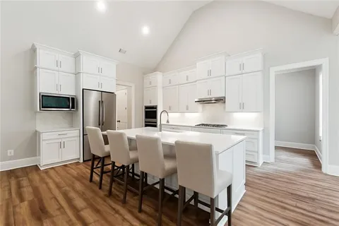 a kitchen with stainless steel appliances a dining table chairs refrigerator and sink