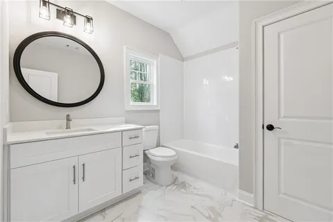 a bathroom with a toilet a sink a mirror and vanity