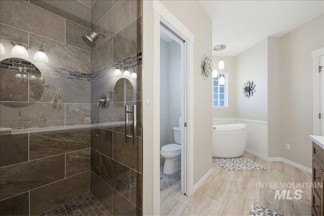 24623 Falcon Lane Caldwell, ID 83607 - Photo 21 of 40 Contemporary bathroom featuring a spacious tiled shower with glass enclosure, a freestanding soaking tub, and neutral-toned floor tile