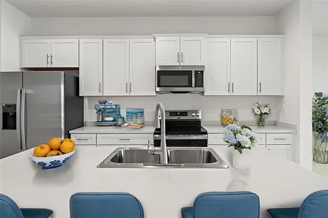a kitchen with stainless steel appliances a white table chairs and a refrigerator