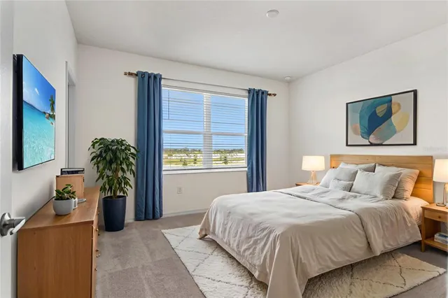 a bedroom with a large bed a potted plant and a window