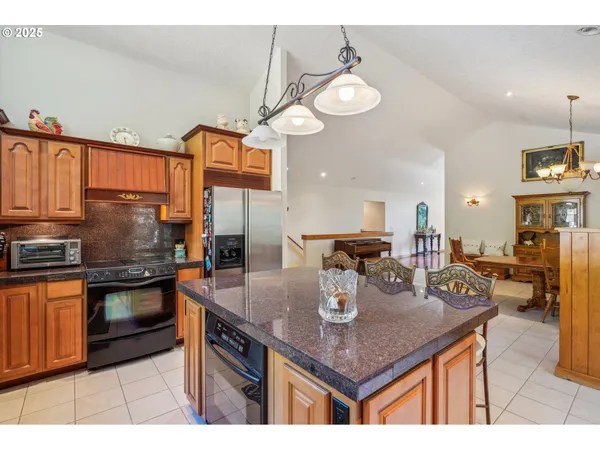 a kitchen with stainless steel appliances granite countertop a sink a stove and chairs