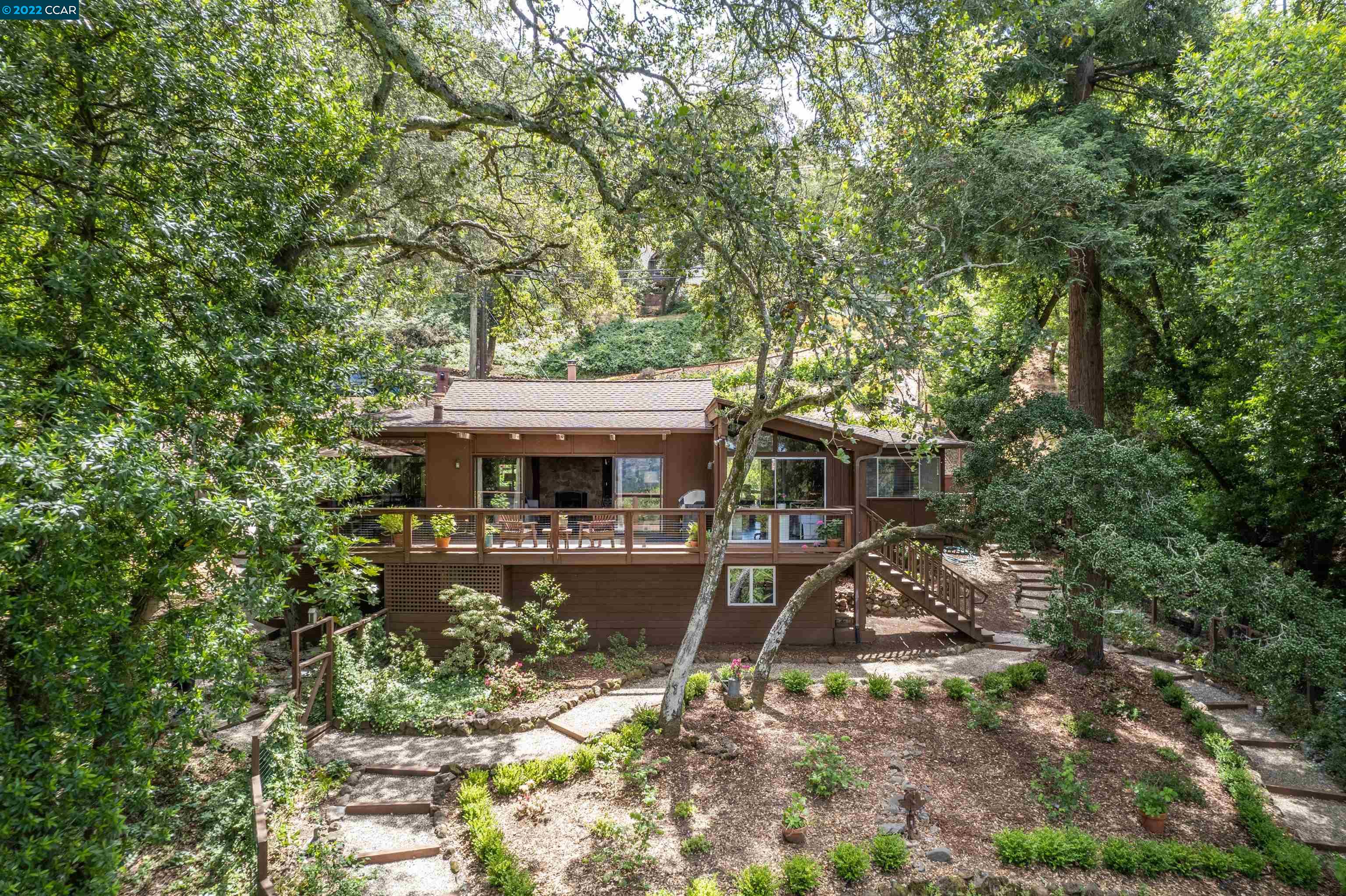 a view of house with yard outdoor seating and covered with trees
