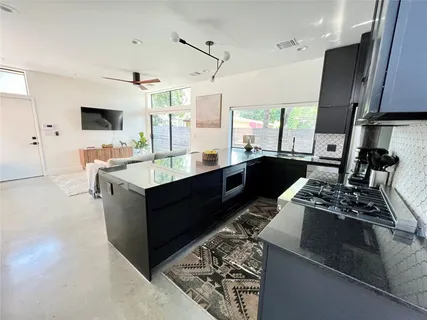 a large kitchen with stainless steel appliances granite countertop a sink stove and refrigerator