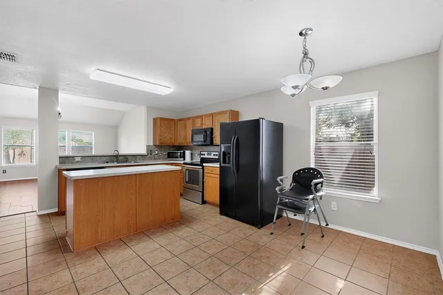 a kitchen with stainless steel appliances kitchen island granite countertop a refrigerator and microwave