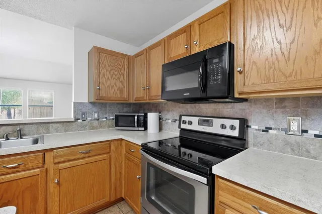 a kitchen with stainless steel appliances a stove a microwave a sink and cabinets