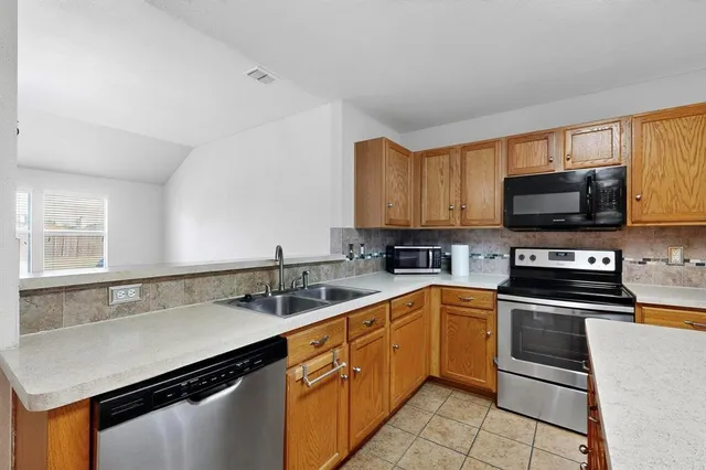 a kitchen with stainless steel appliances a sink dishwasher stove and microwave with wooden cabinets