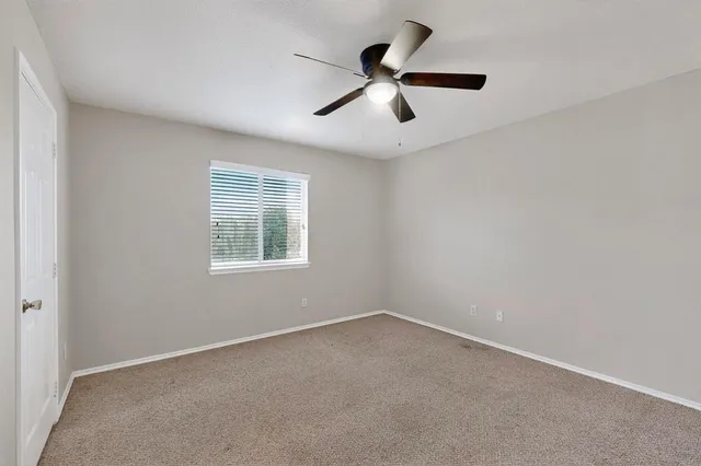 an empty room with a window and a ceiling fan