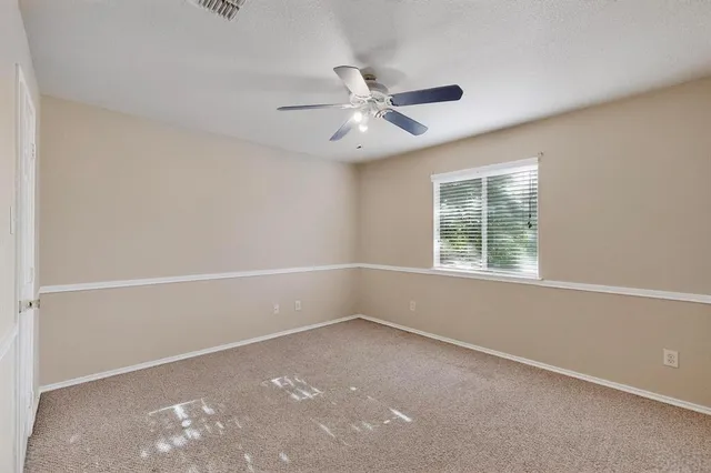 an empty room with a window and ceiling fan
