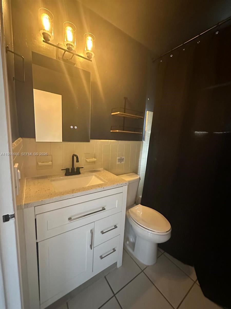 6443 Perry Street Hollywood, FL 33024 - Photo 24 of 24 a bathroom with a granite countertop toilet sink and mirror