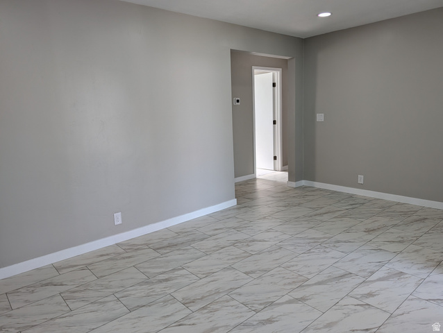 2880 Merton Way Magna, UT 84044 - Photo 29 of 30 Spacious interior featuring large format tile flooring, neutral wall tones, white baseboards, recessed lighting, and a doorway opening to a hall