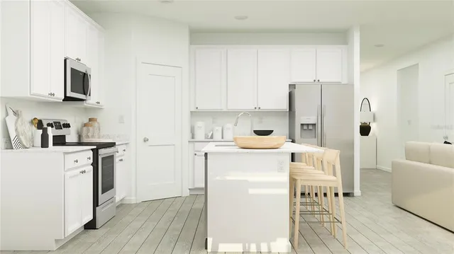 a kitchen with stainless steel appliances a refrigerator a sink and white cabinets with wooden floor