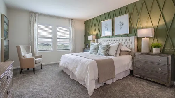 a bedroom with a bed and a lamp on dresser next to a window