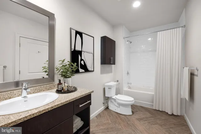 a bathroom with a granite countertop sink toilet and mirror