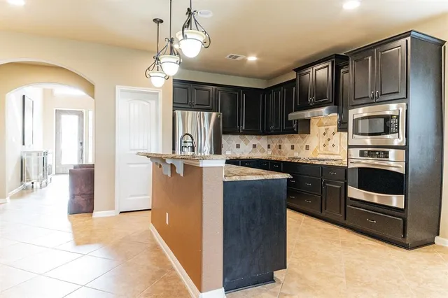 a kitchen with kitchen island granite countertop wooden cabinets a refrigerator oven a sink and dishwasher