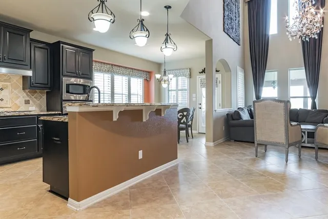 a view of kitchen with stainless steel appliances granite countertop a stove top oven a sink dishwasher a dining table and chairs with wooden floor