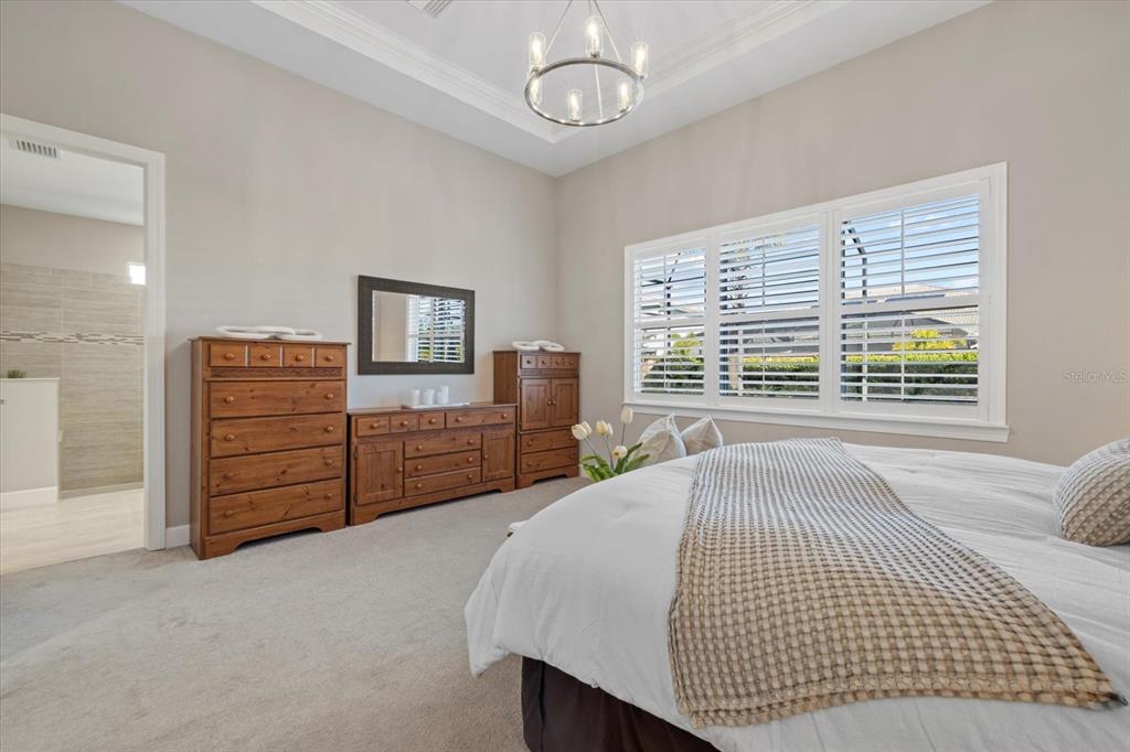 12423 Blue Hl Trail Lakewood Ranch, FL 34211 - Photo 23 of 74 a spacious bedroom with a bed a dresser and a large window