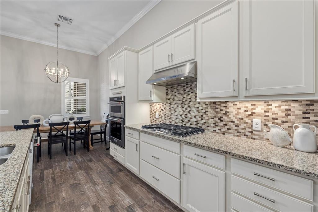 12423 Blue Hl Trail Lakewood Ranch, FL 34211 - Photo 9 of 74 a kitchen with stainless steel appliances granite countertop a stove a sink dishwasher and white cabinets with wooden floor
