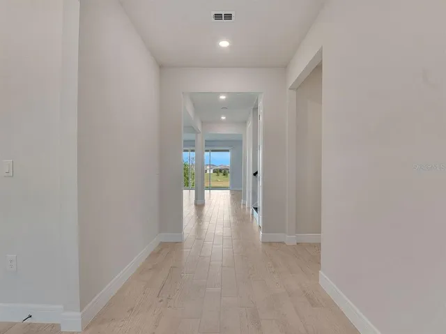 a view of a hallway with wooden floor and a bathroom