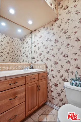 a bathroom with a granite countertop toilet sink and mirror