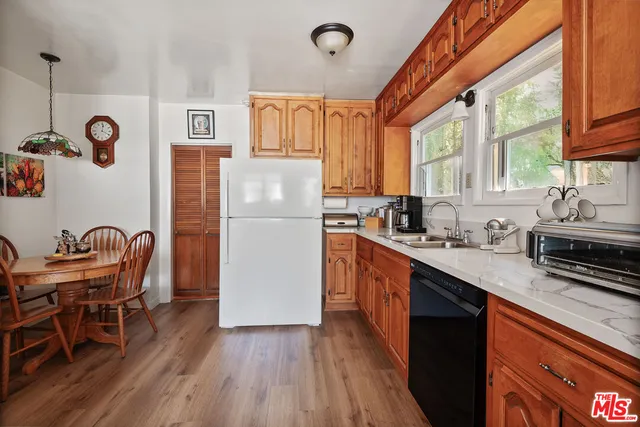 a kitchen with stainless steel appliances granite countertop a refrigerator a sink dishwasher a dining table and chairs with wooden floor