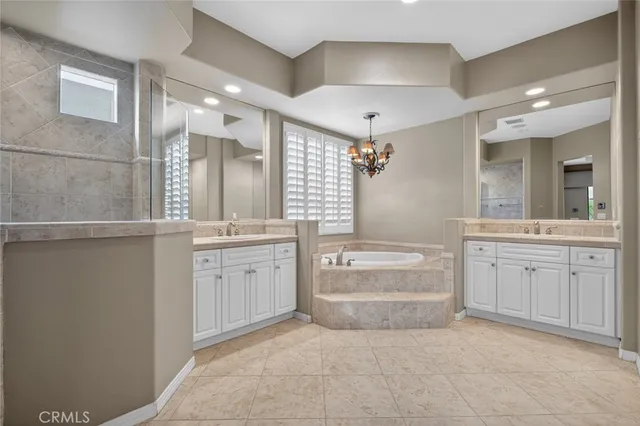 a view of an empty room with chandelier fan and wooden floor