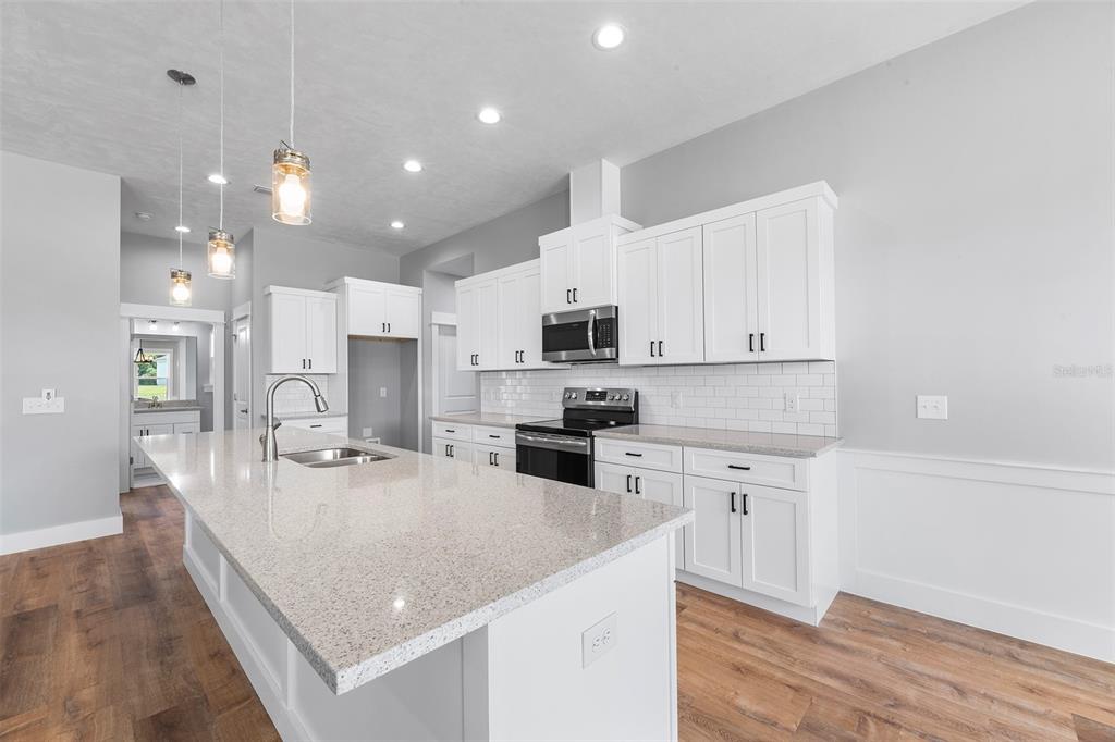 0 Southwest Meadow View Lake City, FL 32024 - Photo 7 of 31 a large kitchen with kitchen island a stove a sink a refrigerator and white cabinets with wooden floor