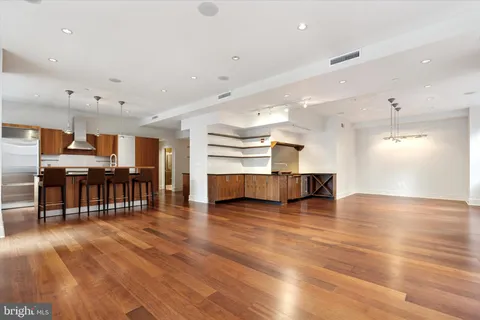 an empty room with wooden floor and a kitchen