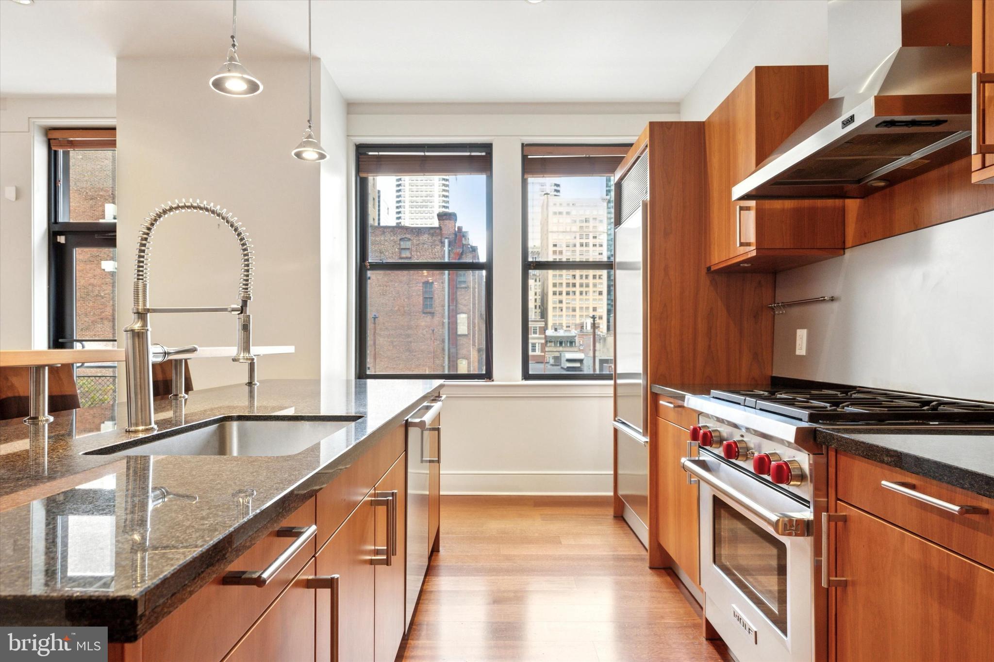 1515 Locust Street, Unit 400 Philadelphia, PA 19102 - Photo 5 of 25 a kitchen with stainless steel appliances granite countertop a stove and a sink with large windows