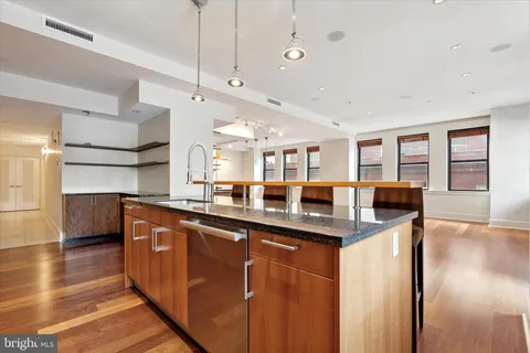 a kitchen with stainless steel appliances granite countertop a sink a stove and a wooden floors