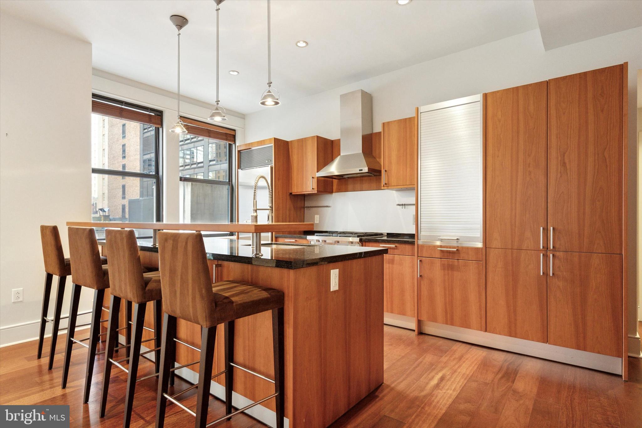 1515 Locust Street, Unit 400 Philadelphia, PA 19102 - Photo 8 of 25 a kitchen with stainless steel appliances granite countertop a stove a refrigerator a dining table and chairs with wooden floor