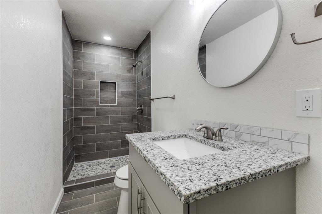 2908 Scottsbluff Drive Dallas, TX 75228 - Photo 17 of 34 a bathroom with a granite countertop sink a mirror and shower