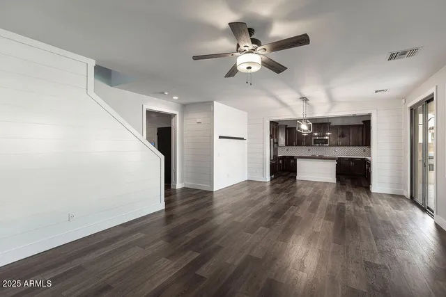 a view of a kitchen with a sink a refrigerator a ceiling fan and wooden floor