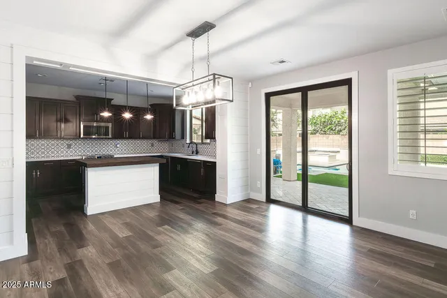 a kitchen with stainless steel appliances granite countertop a refrigerator a sink dishwasher a stove and white countertops with wooden floor