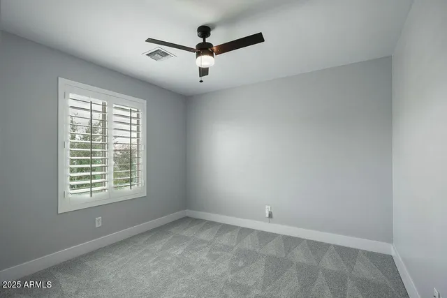 an empty room with a window and a fan