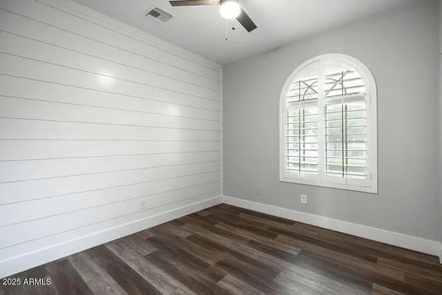 an empty room with wooden floor chandelier and windows