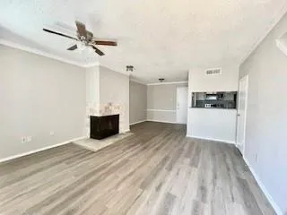 a view of a livingroom with a fireplace a ceiling fan and wooden floor