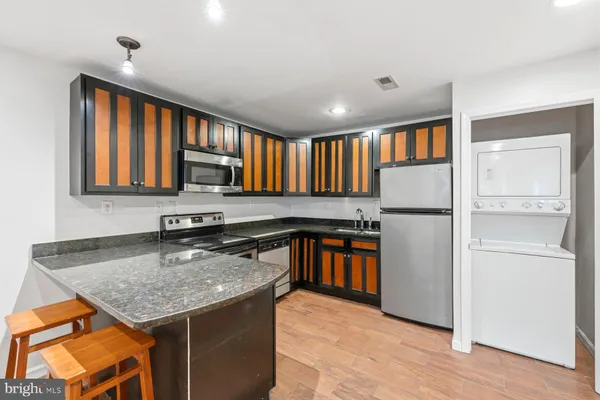 a kitchen with stainless steel appliances granite countertop a refrigerator a stove and a sink with wooden cabinets